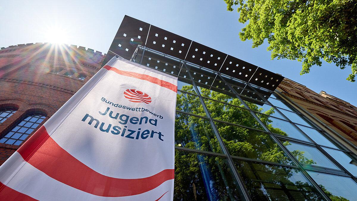 Jugend musiziert Fahne vor einer gläsernen Häuserfront